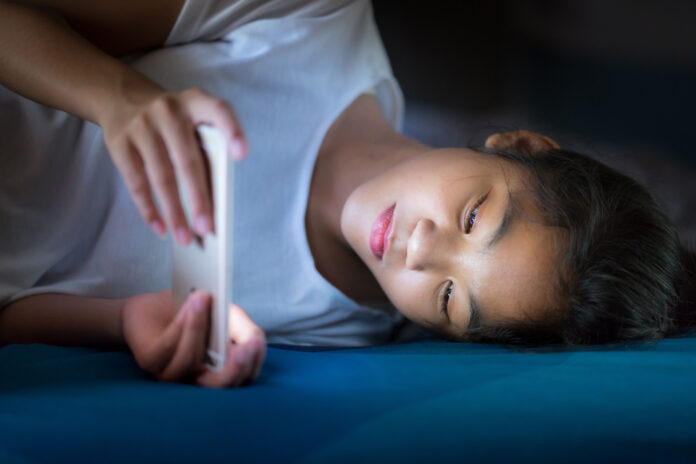 Teenager,Girl,Lying,In,Bed,Playing,A,Smartphone,In,Internet