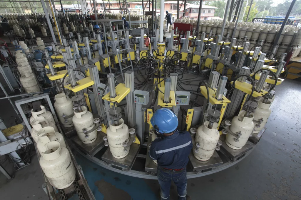 Trabajadores de la planta de Austrogas, en la Panamericana Norte, durante su trabajo cotidiano. /XCA