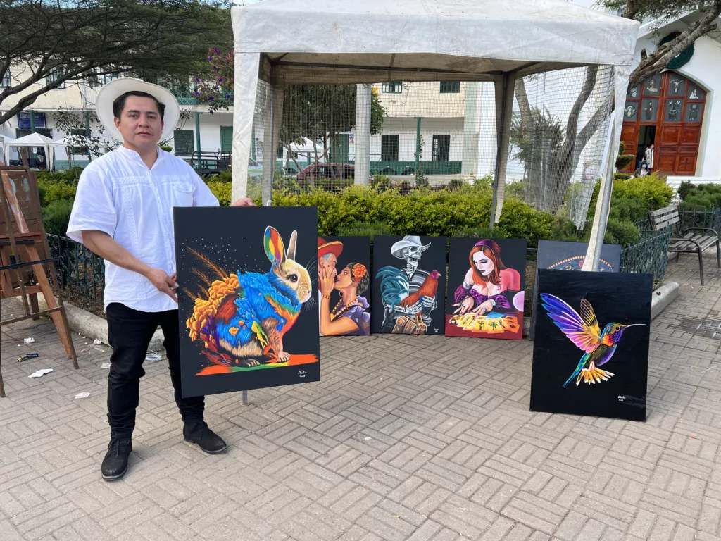 Cristian Quito muestra algunos de sus cuadros en una exposición en el parque central de la parroquia San Juan, del cantón Gualaceo. Cortesía