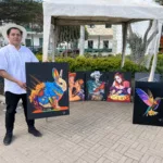 Cristian Quito muestra algunos de sus cuadros en una exposición en el parque central de la parroquia San Juan, del cantón Gualaceo. Cortesía