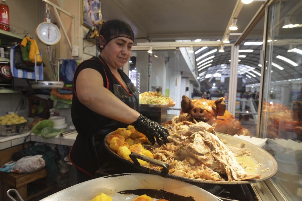 María Chocho, comerciante del mercado 10 de Agosto, prepara un plato de hornado. Esta comida es característica de la ciudad de Cuenca. XCA