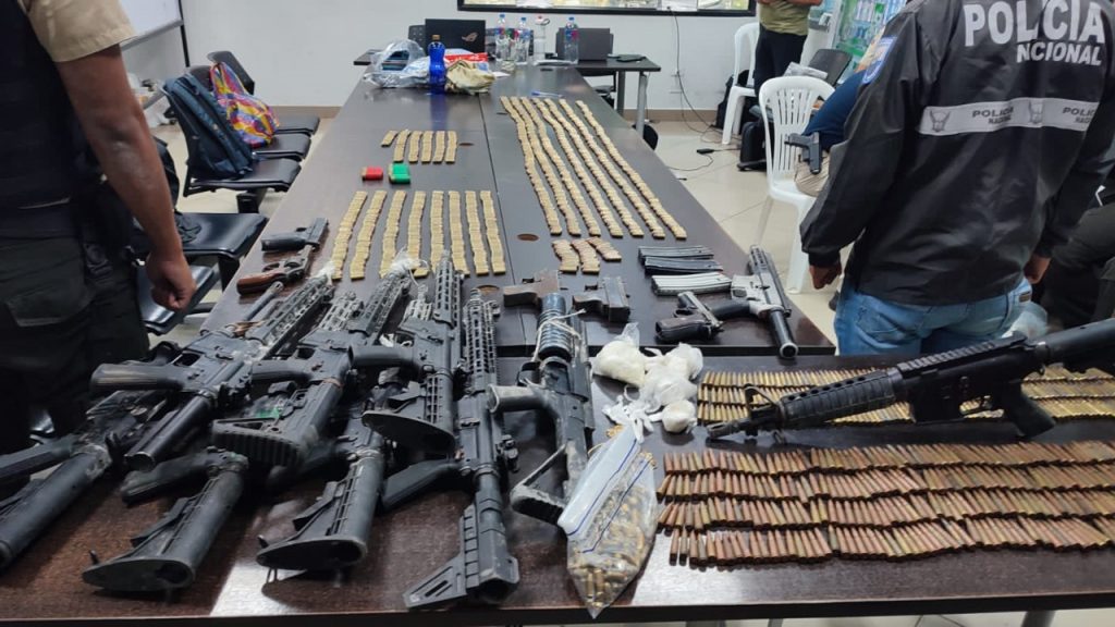 Armas incautadas sobre una mesa son presentadas por la Policía Nacional.