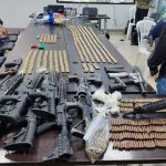 Armas incautadas sobre una mesa son presentadas por la Policía Nacional.