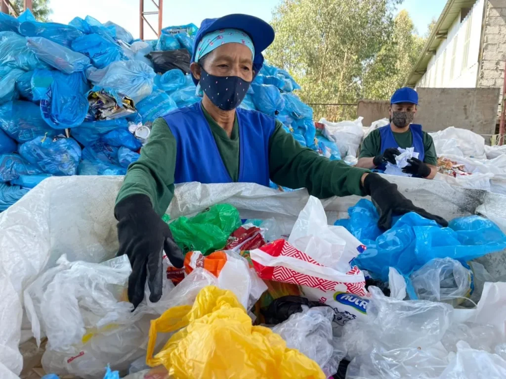 Una mujer muestra los productos que recicla y que llegan en las fundas celestes.