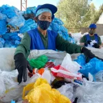 Una mujer muestra los productos que recicla y que llegan en las fundas celestes.