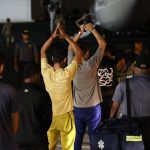 Migrantes esperan frente a un avión para ser deportados a Colombia este martes, en el aeropuerto Marcos A. Gelabert en Ciudad de Panamá (Panamá). El primer vuelo de retorno de migrantes irregulares que cruzaron la peligrosa selva del Darién, financiado por Estados Unidos en el marco de un acuerdo con Panamá, salió este martes de la capital del país centroamericano con destino a la ciudad de Medellín, en Colombia. EFE