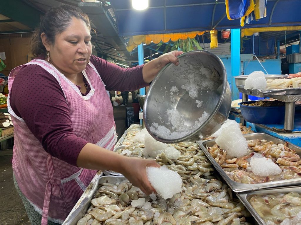 Ofelia Maya, trabajadora de una pescadería en el sector de la Feria Libre, coloca el hielo sobre los camarones para mantener el producto fresco ante los apagones.