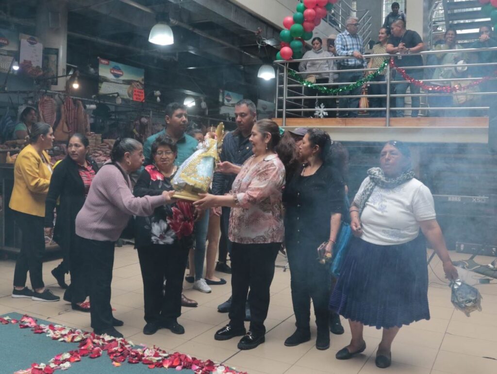 Rosa Matute, dirigente de la ‘Asociación Unión y Progreso’, recibe la imagen del Niño Viajero en su visita al Mercado 9 de Octubre.
