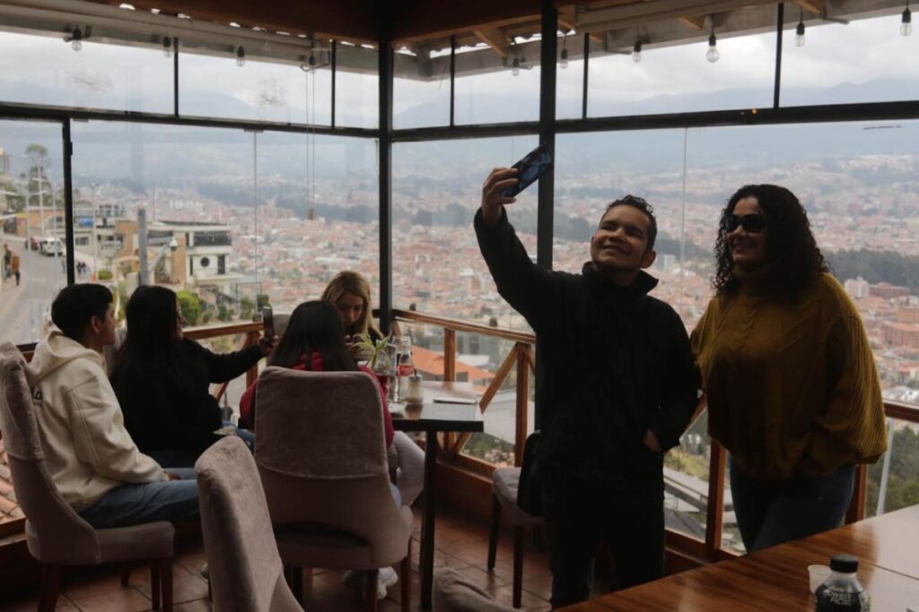 Turistas disfrutan en un restaurante del mirador de Turi, con vista panorámica de Cuenca.