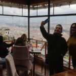 Turistas disfrutan en un restaurante del mirador de Turi, con vista panorámica de Cuenca.