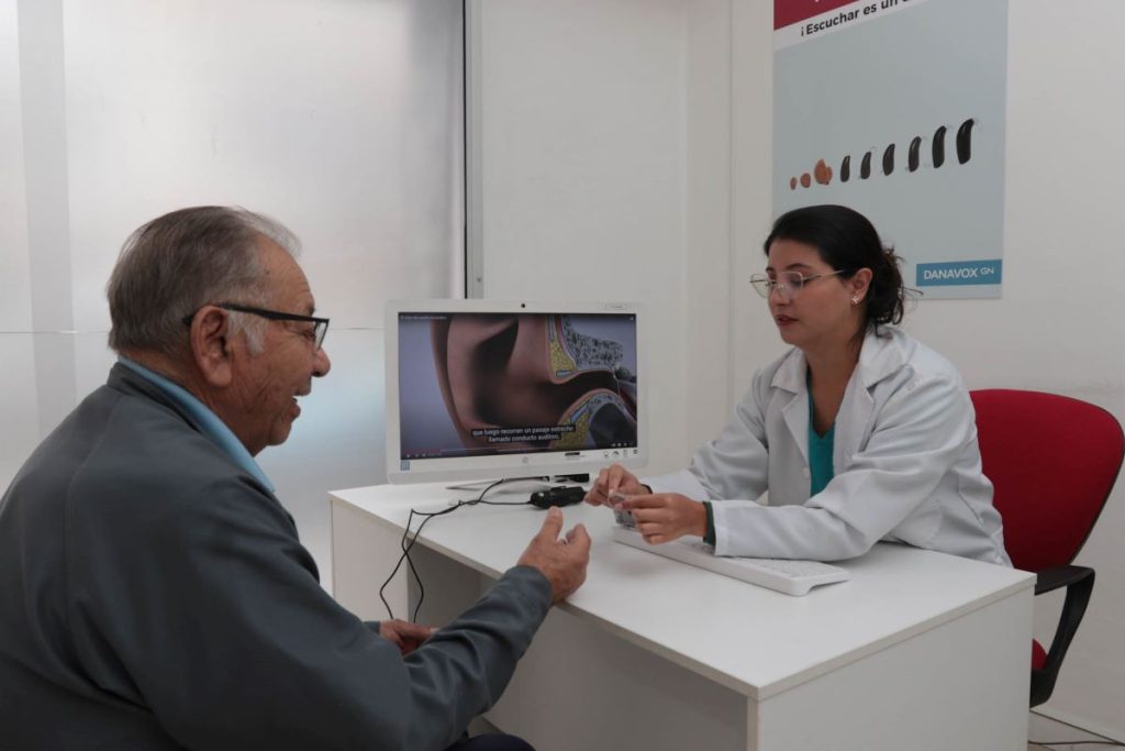 Marcela Loaiza, audióloga del Centro "Audición para Todos", asesora a Franklin Cárdenas sobre el uso adecuado de audífonos.