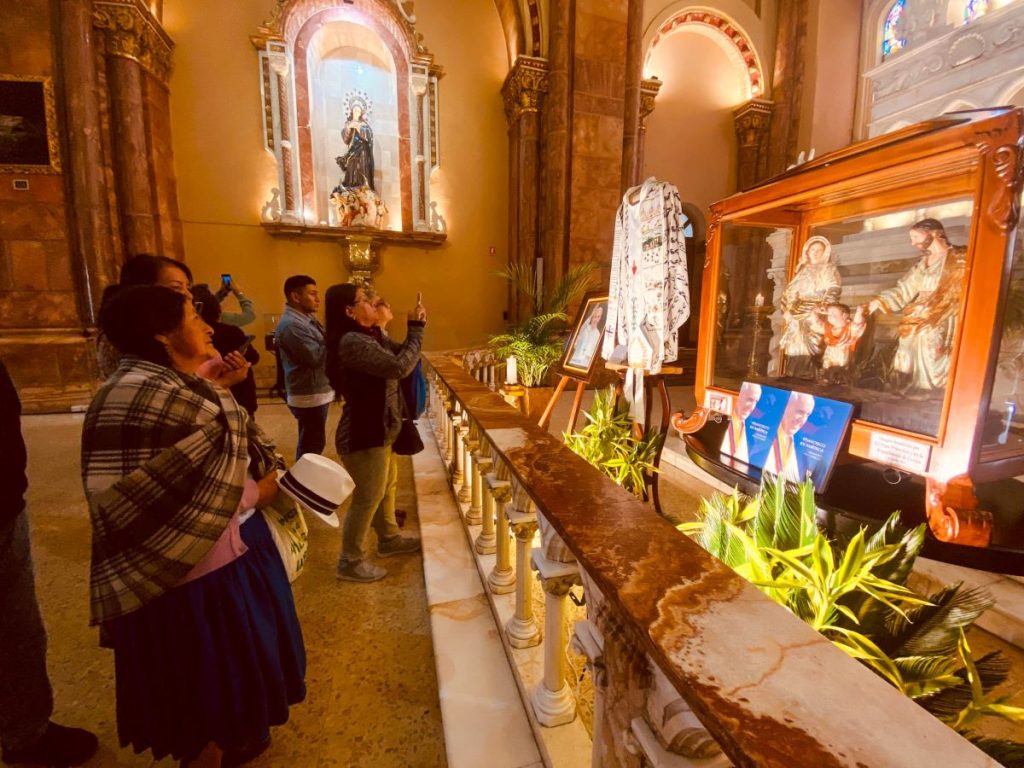 Devotos oran en la Catedral de la Inmaculada Concepción, donde se exhibe la casulla, la mitra y la estola utilizadas por el papa Francisco en su visita al Ecuador en 2015.
