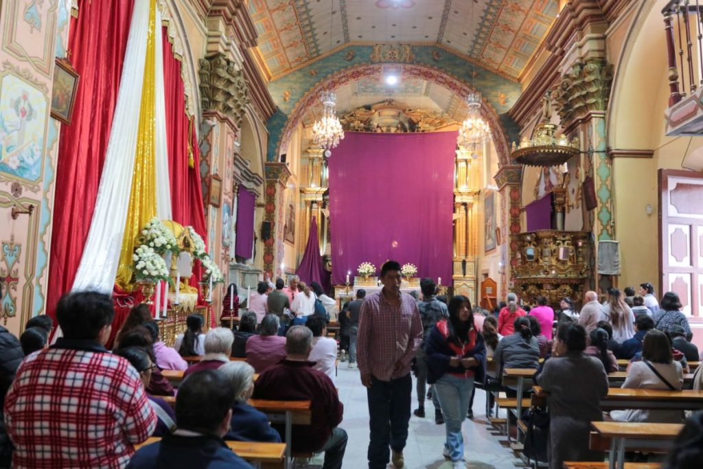 Devotos oran en la iglesia del Carmen de la Asunción, donde las imágenes religiosas permanecen cubiertas con mantos color púrpura.