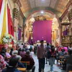 Devotos oran en la iglesia del Carmen de la Asunción, donde las imágenes religiosas permanecen cubiertas con mantos color púrpura.