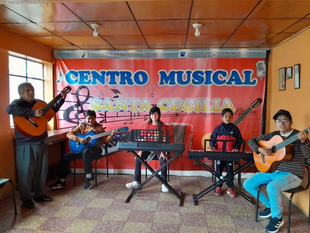 Rafael Auquilla, director del Centro Musical Santa Cecilia, junto a un grupo de alumnos.