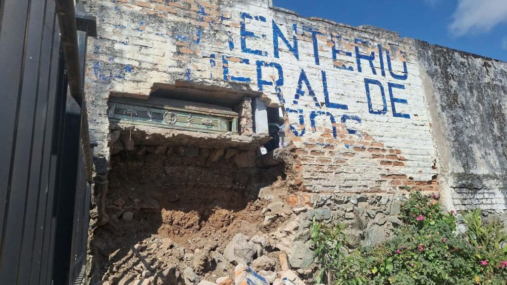 La caída de un muro en el Cementerio General de la parroquia Baños, dejó expuesto un féretro. /Cortesía